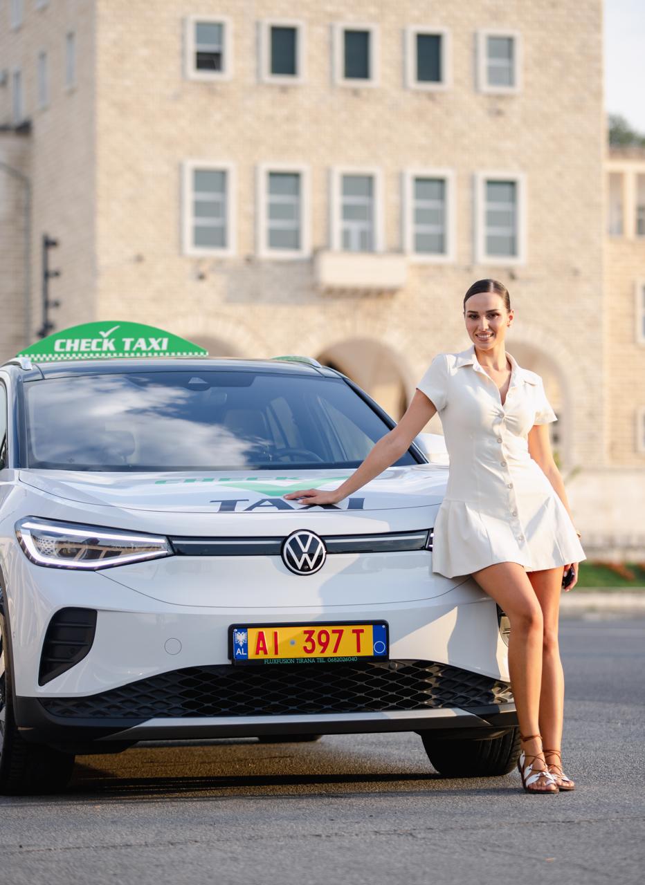 Smiling woman leaning on Check Taxi car near Air Albania Stadium in Tirana
